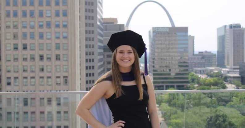 Jenna DeBarry in a graduation cap with the St. Louis skyline behind her.
